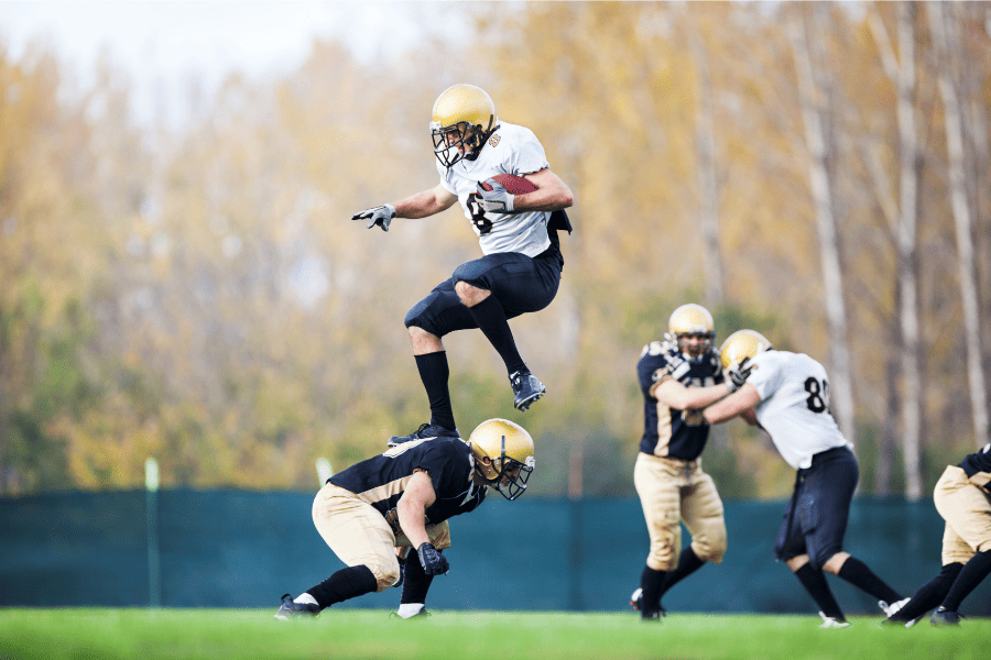 Football Player Jumping Over another Player